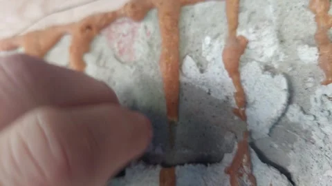 Hand checking dried polyurethane foam insulation drips on a concrete wall Stock Footage 336508067