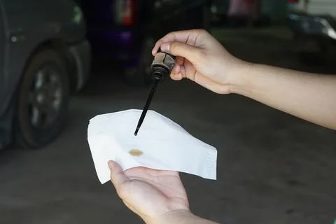 Hand checking engine oil level with dipstick and tissue paper. Automotive mainte Stock-Fotos