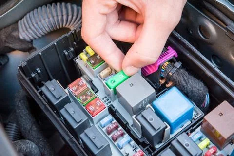 Hand checking a fuse in a car engine Stock Photos