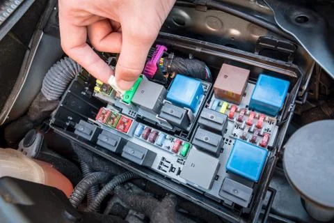 Hand checking a fuse in a car engine Stock Photos