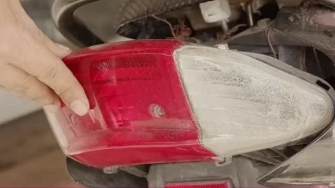 Hand checking loose red and white motorcycle tail light housing Video stock 320129870