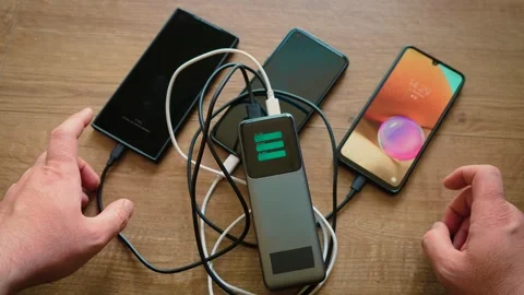 Hand checking smartphone battery level during charging from power bank with Stock Footage 339344187