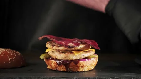Hand of a chef in black gloves prepares a burger or cheeseburger on a slate Video stock 147098897