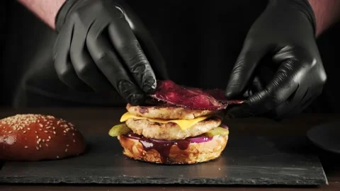 Hand of a chef in black gloves prepares a burger or cheeseburger on a slate Stock-Footage 149055442
