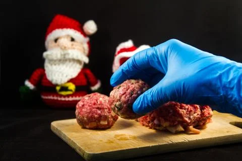 Hand of a chef with blue gloves posing Raw meatballs on a wooden cutting boar Stock Photos