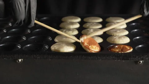 Hand of chef flip small round pancakes on hot surface delicious snack Stock Footage 321054870