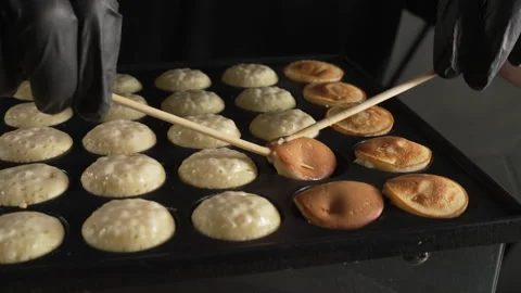 Hand of chef flip small round pancakes on hot surface delicious snack Stock Footage 321055113