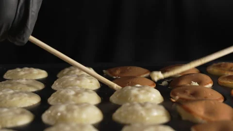 Hand of chef flip small round pancakes on hot surface delicious snack Stock Footage 321055114