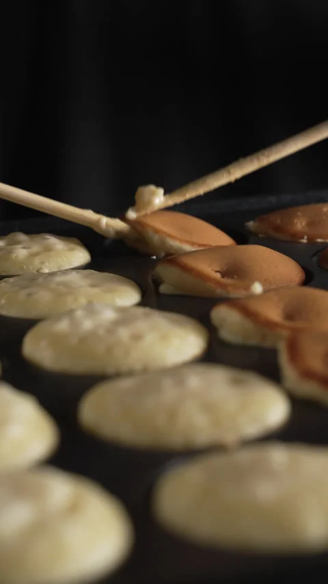 Hand of chef flip small round pancakes on hot surface delicious snack Stock Footage 321055141