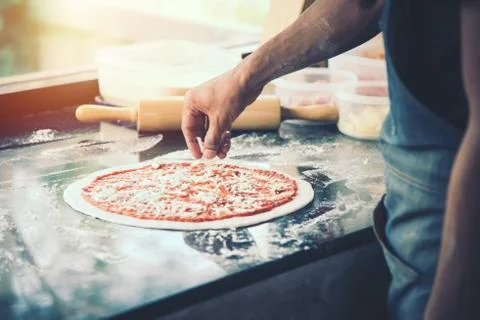 Hand Chef preparing spread cheese on pizza on marble table Stock Photos