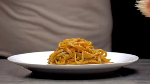 Hand of a chef puts a parmesan and basil leaf on top of the pasta Stock Footage 97145157
