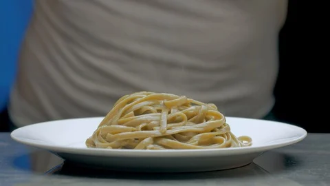 Hand of a chef puts a parmesan and basil leaf on top of the pasta Stock Footage 97146422
