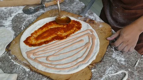 Hand of Chef spreading tomato sauce on pizza dough with a metal ladle 스톡 동영상 81575990