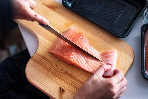 Hand chef using knife slice raw salmon on chopping board Stock Photos