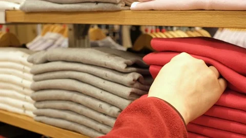 A hand chooses clothes on shelves in the store close-up. Stock Footage 167367710