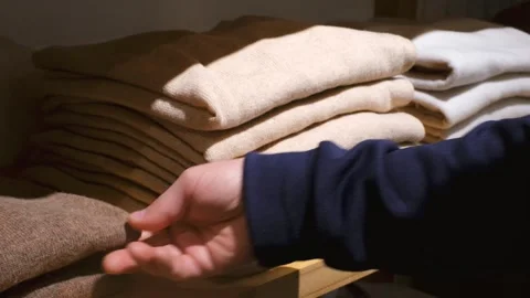 A hand chooses clothes on shelves in the store close-up. Stock Footage 259674079