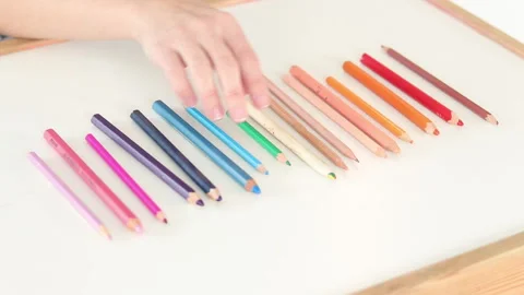 Hand choosing blue colored pencil from rainbow gradient on white table Stock Footage 331718990