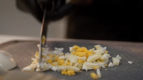 Hand chopping boiled egg on grey plastic cutting board Stock Footage 121364329