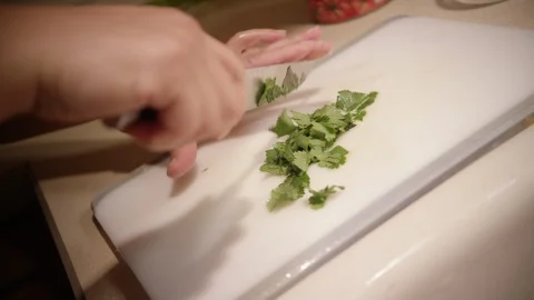 Hand chopping up parsley on white cutting board Stock Footage 123736077
