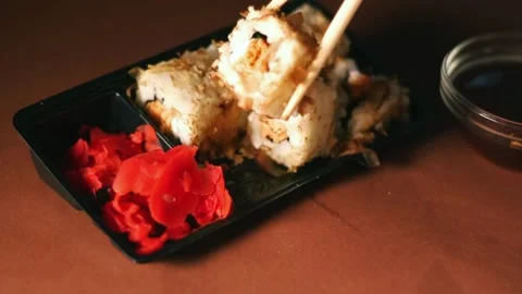 Hand with chopsticks taking portion of sushi roll. Sushi rolls with salmon Stock Footage 293195591