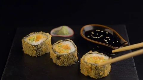 Hand with chopsticks taking roll sushi from dark plate Stock Footage 69816384