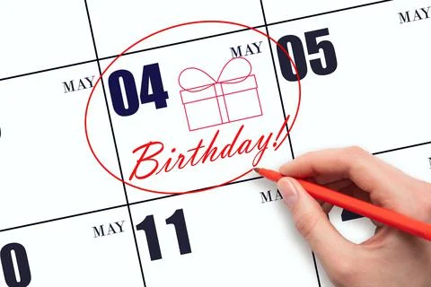 The hand circles the date on the calendar 4 May, draws a gift box and writes  Stock Photos