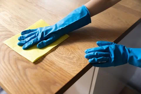 Hand of cleaner wearing blue protective rubber gloves, washing tabletop Stock Photos