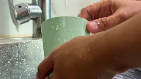 Hand cleaning black pan with water, kitchen sink scene, dishwashing and Stock Footage 345293668