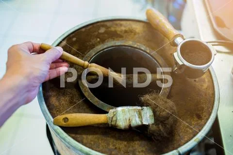 Hand cleaning with brush on wooden bucket of ground coffee from coffee machin Stock Photos