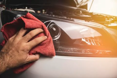 Hand is cleaning car headlight with a using red microfiber cloth. Foto stock