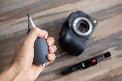 Hand cleaning digital camera sensor from dust with air blower and brush Stock Photos