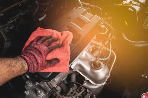 Hand is cleaning engine cover with a using red microfiber cloth. Stock Photos