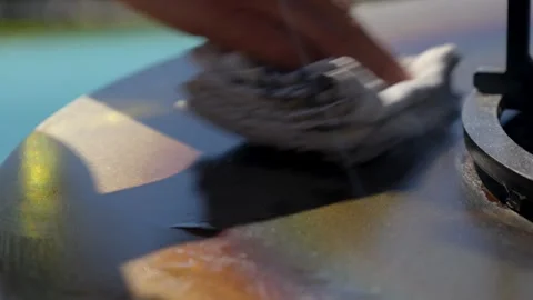 Hand cleaning a hot fire pit surface with a cloth Stock Footage 327721241