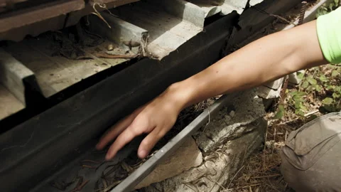 Hand cleaning rainwater gutter from leaves and debris Stock Footage 280307811