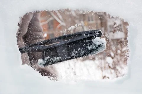 Hand cleaning snow-covered window of car with brush Stock Photos