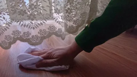 Hand cleaning the wooden floor while curtains swaying in the wind Stock Footage 336362145