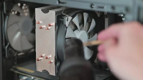 A hand cleans a cooling fan inside a computer case using a small tool. This 库存影片 337112807
