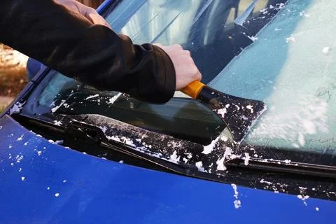 Hand cleans windshield of car from ice Stock Photos