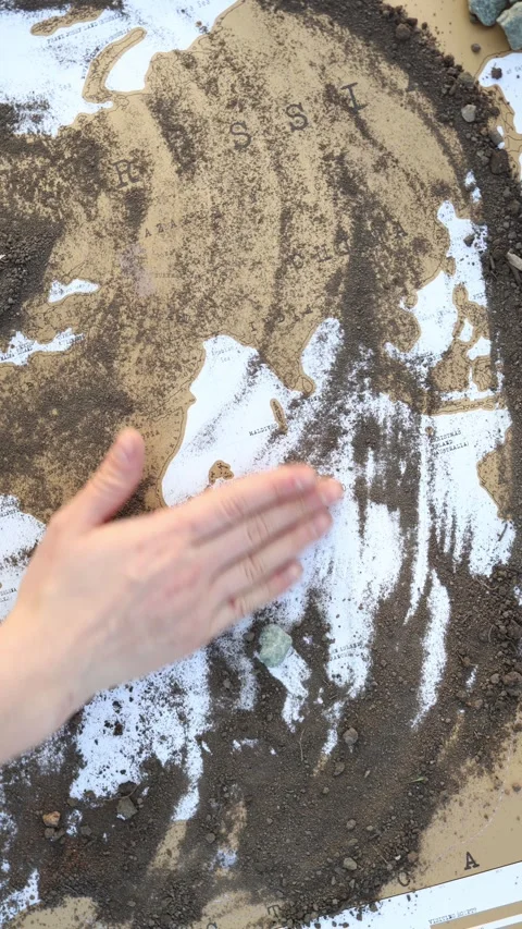 Hand clears soil from a world map Stock-Footage 337941603