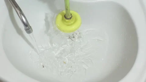 A hand clears a washbasin drain with a plunger 스톡 동영상 342392077