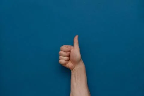 Hand clenched fist thumbs up on a blue background. Stock Photos