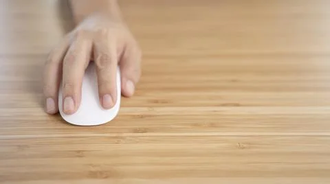 Hand Clicking on white computer mouse on the wooden desk table. Stock Photos
