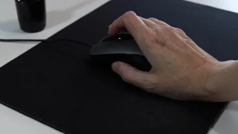 Hand clicks and scrolls on a black wired optical mouse on a mouse pad Stock Footage 341950688