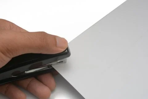 A hand is clipping using stapler on a bunch of paper. 写真素材