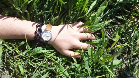 Hand with a clock on the grass Stock Footage 76758799