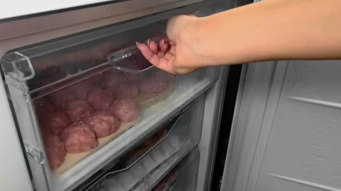 Hand closes the freezer drawer, there are meatballs in the drawer Stock Footage 261406938