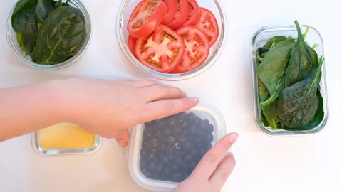 Hand closes the lid on glass box with blueberries on white background, top view. Stock Footage 255685308