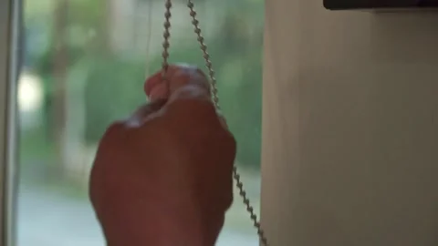 Hand closing a window curtain using a pull cord system. Stock Footage 338428970