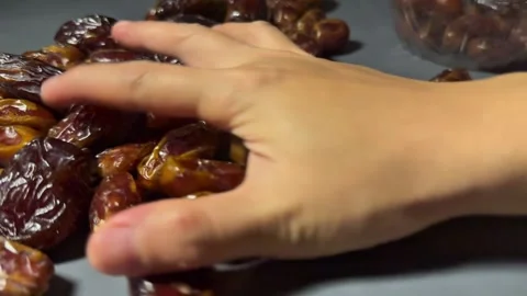 Hand Collecting Dried Dates to Place Back into Container on Dark Background Stock Footage 328136950