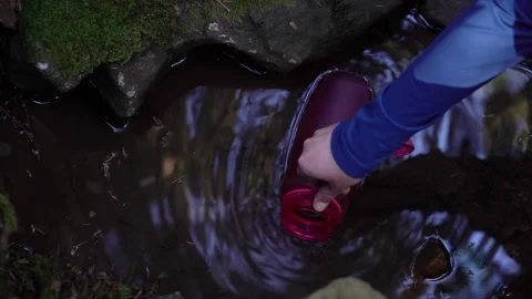 Hand collects water from a small stream in a peaceful outdoor setting Vídeos de archivo 334861657